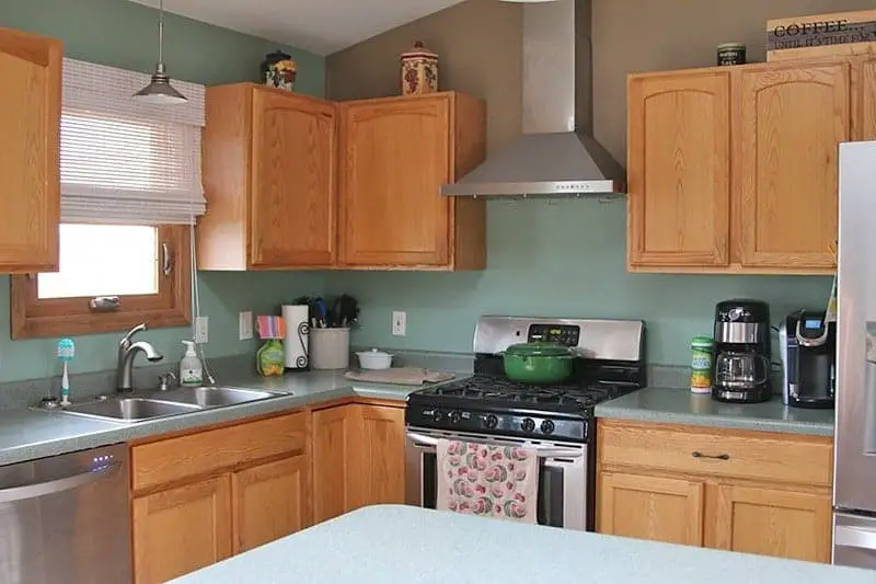 clean kitchen with orange wood cabinets and green counters and walls